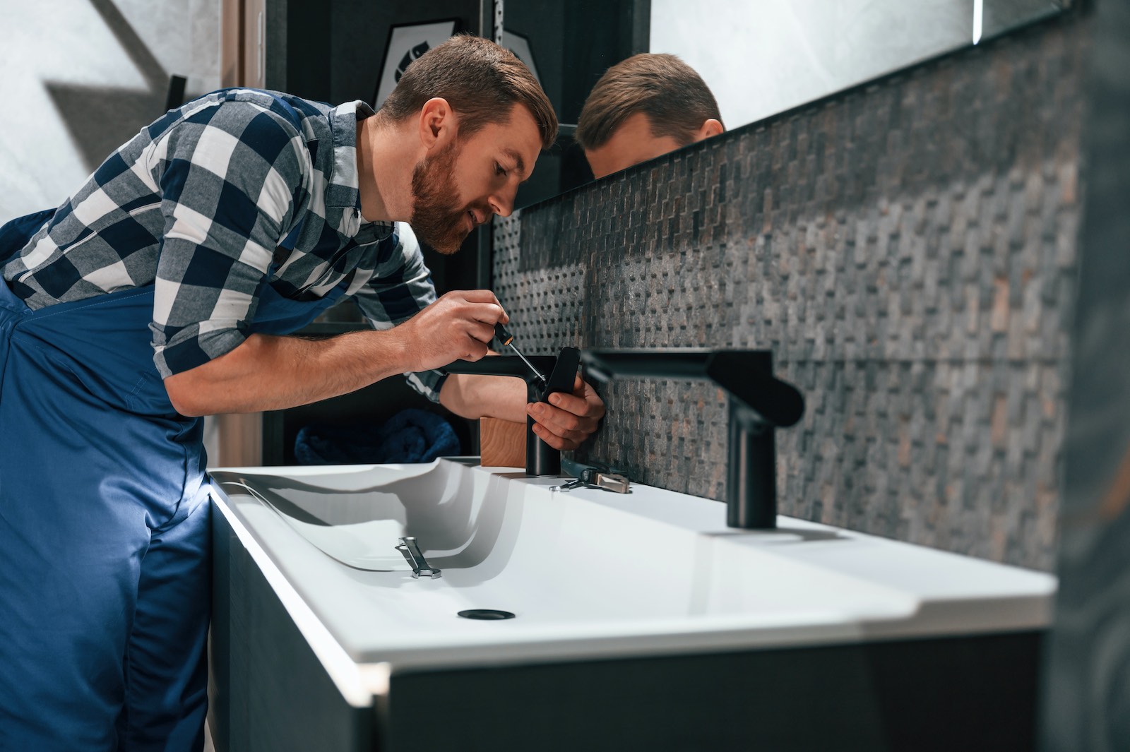 Plumber repairing a bathroom basin and tap