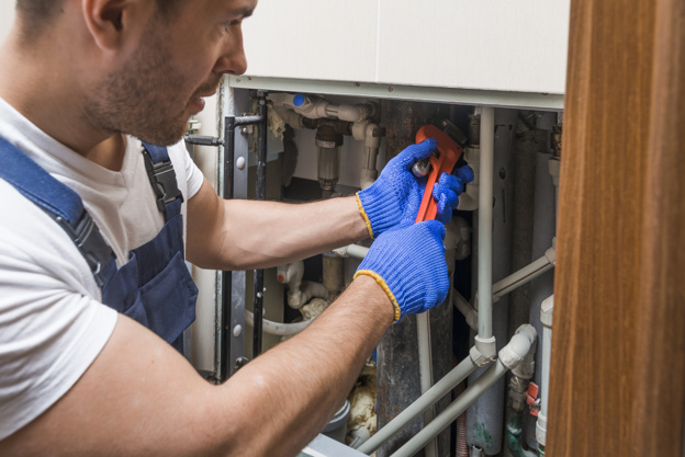 Technician working on exposed water and drain pipes